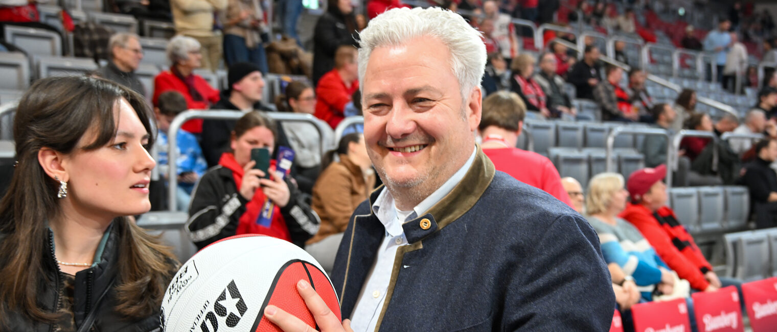 HWK-Präsident Matthias Graßmann hält lächelnd einen Basketball in den Händen.