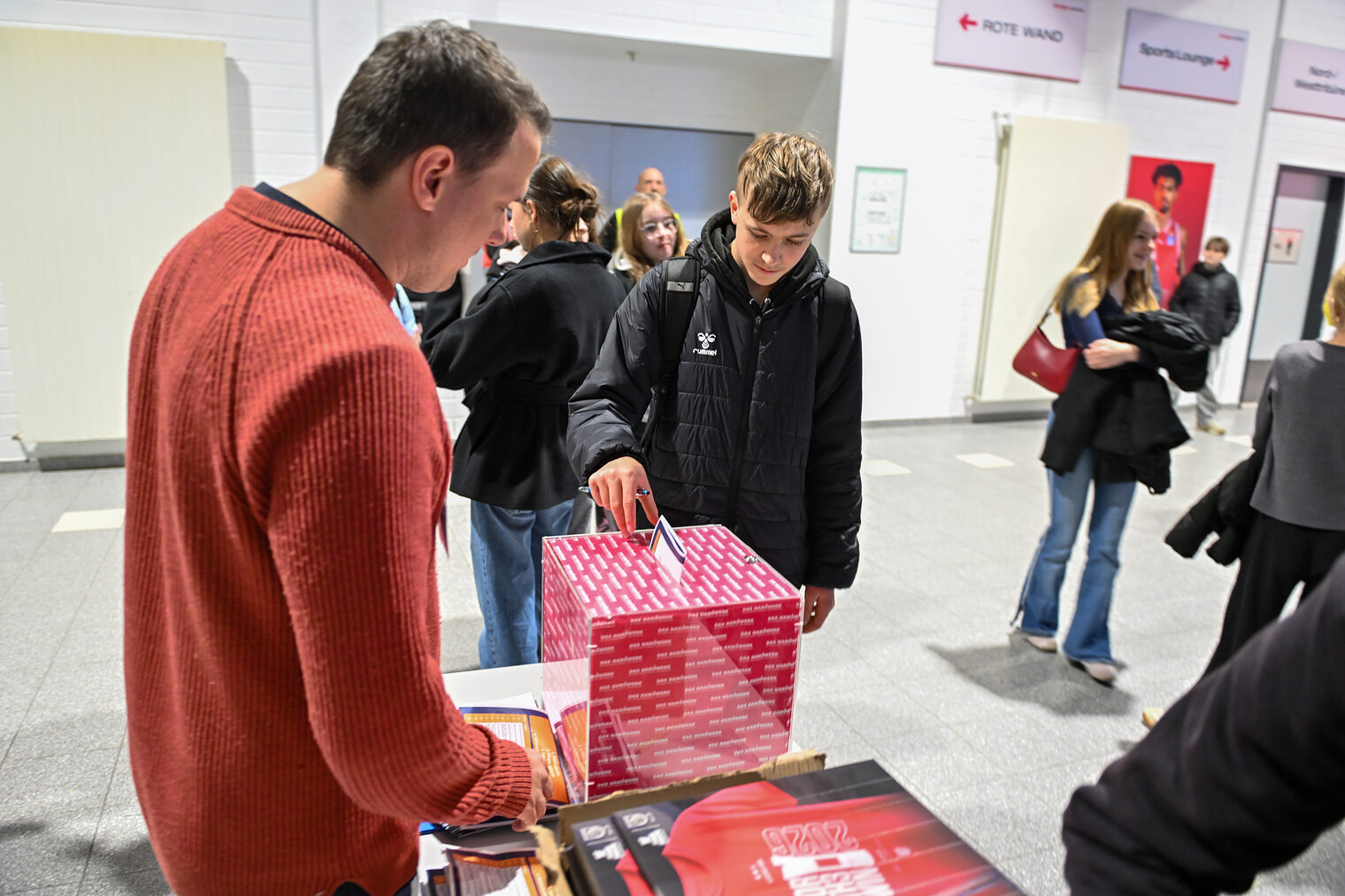 Ein Schüler wirft seine Laufkarte mit seinem Quiz in die Losbox.