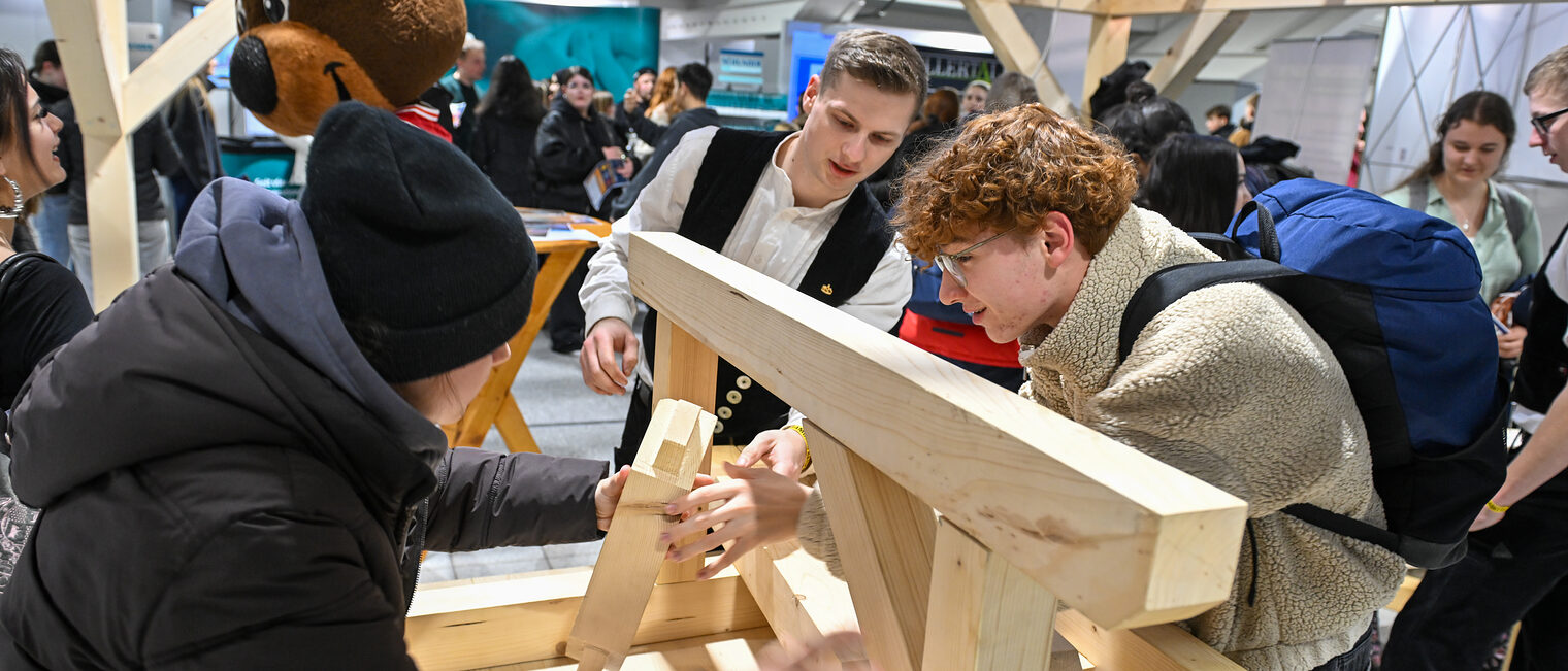 Ein Schüler fügt eine Holzverbindung unter Aufsicht zusammen.