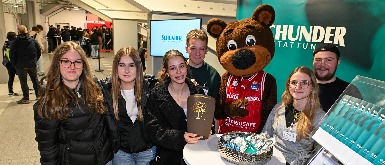 Eine Gruppe Schülerinnen posiert mit dem Team von Schunder Bestattungen und einer Urne.