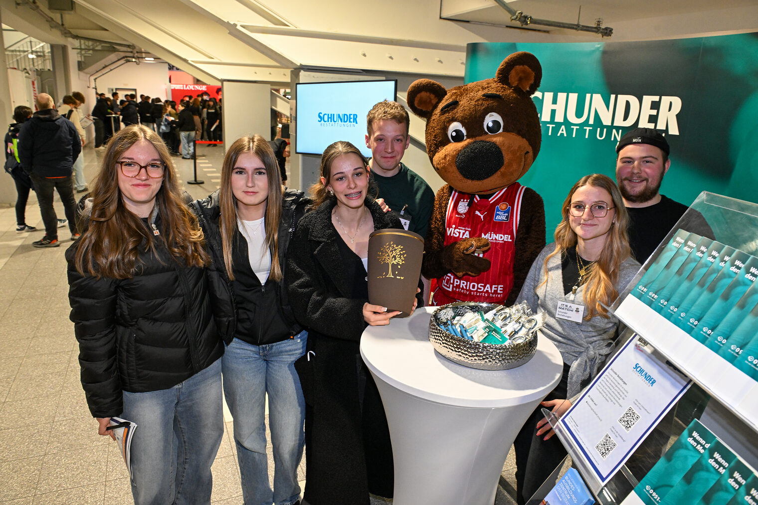 Eine Gruppe Schülerinnen posiert mit dem Team von Schunder Bestattungen und einer Urne.