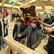 Zwei Schüler hämmern Nägel in einen Holzbalken während Maskottchen Freaky zusieht.