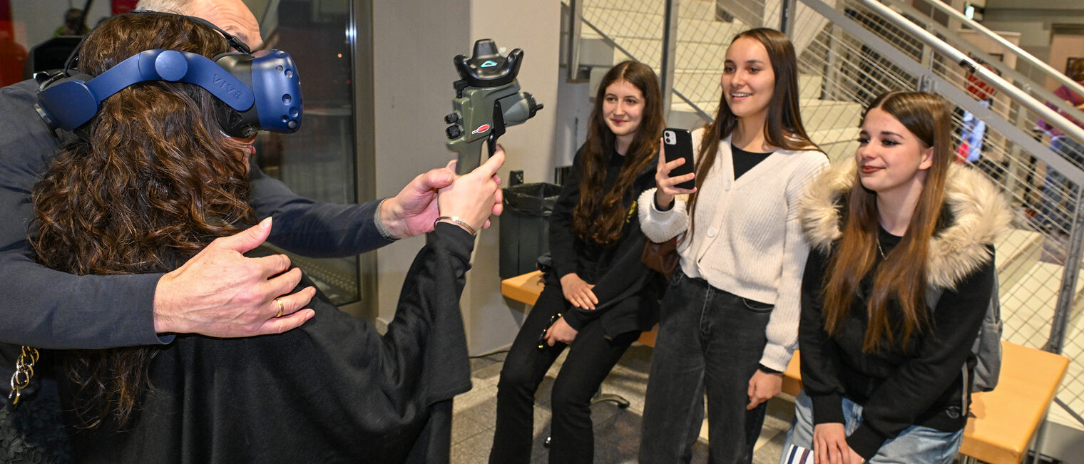 Eine Schülerin trägt eine VR-Brille und benutzt das SIM-Spray zum digitalen Lackieren.