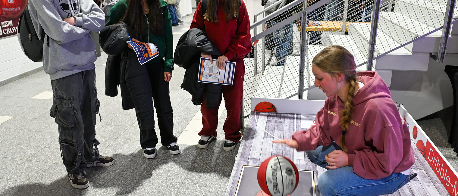 Eine Schülerin versucht sich an der Dribbelchallenge während drei weitere Schülerinnen zusehen.