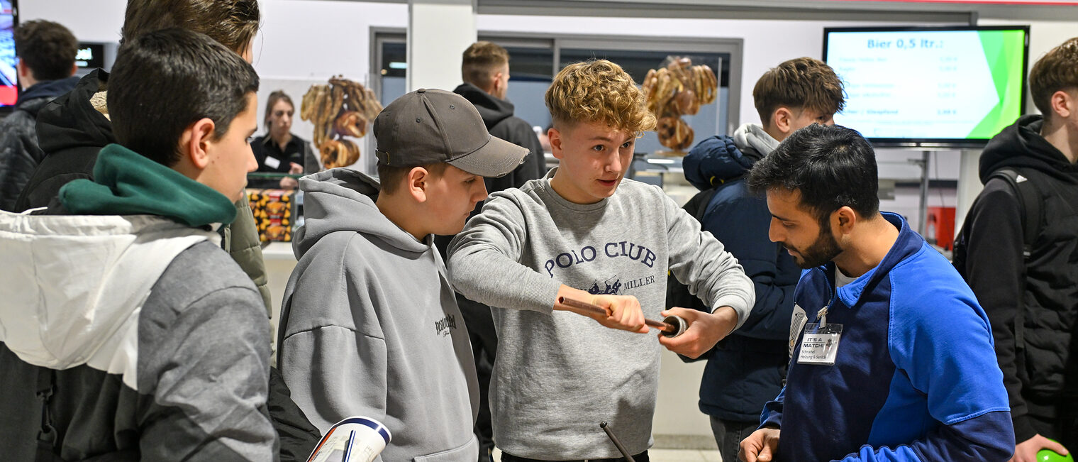 Ein Schüler schleift unter Aufsicht ein Metallrohr zu.