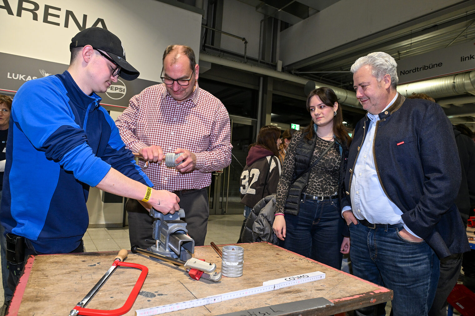 Ein Mann schleift an einem der Stände ein Metallrohr zurecht, während HWK-Präsident Matthias Graßmann zusieht.