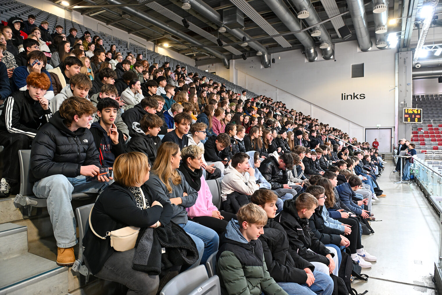 Die Schülerinnen und Schüler sitzen bei einem Vortrag auf der Nordtribüne.