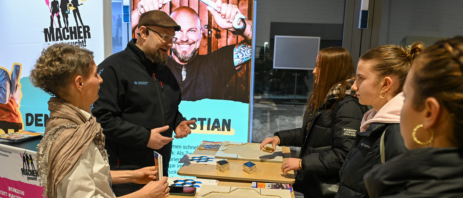 Udo Pfadenhauer von der HWK erklärt Schülerinnen die Fliesenlegechallenge.