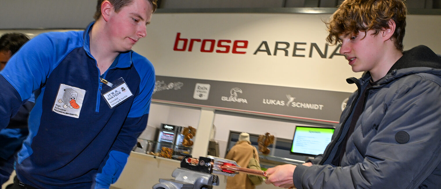 Ein Schüler schneidet unter Anleitung ein Metallrohr aus Kupfer zu.
