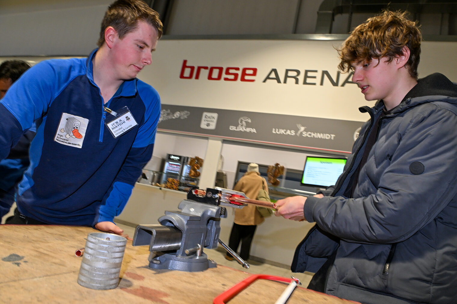 Ein Schüler schneidet unter Anleitung ein Metallrohr aus Kupfer zu.