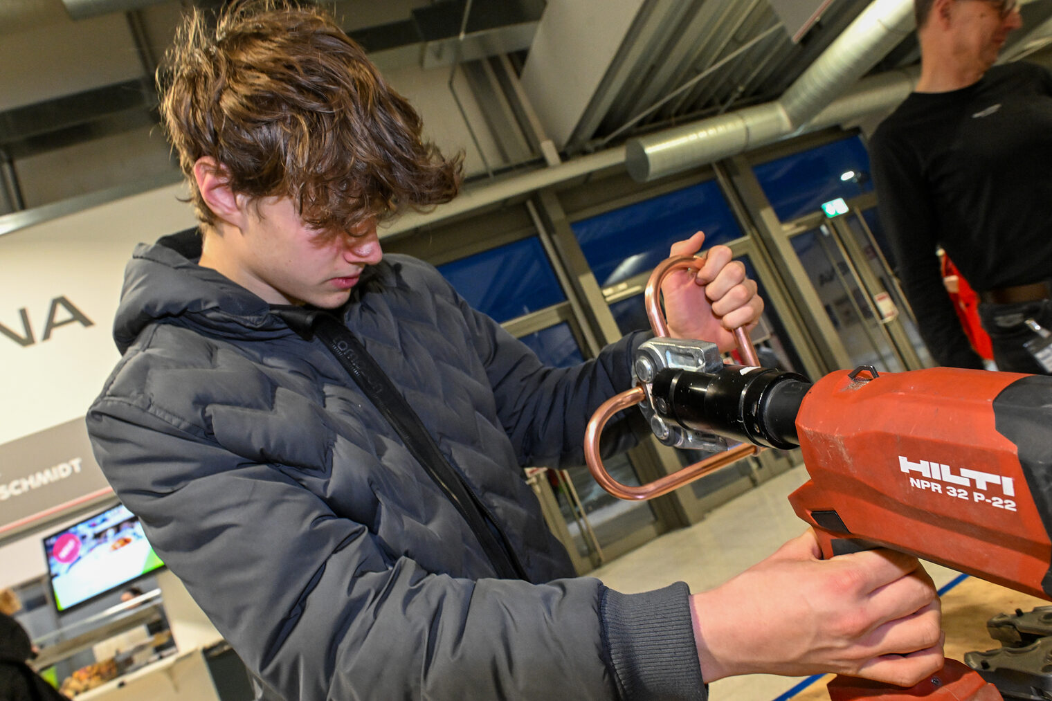 Ein Schüler biegt ein Herz aus Kupferrohren am Schraubstock zurecht.