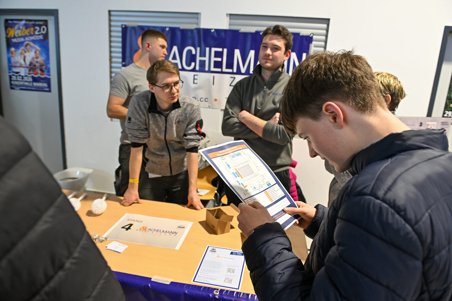 Ein Schüler füllt einen Zettel mit einem Quiz am Stand von Kachelmann Bad und Heizung aus.
