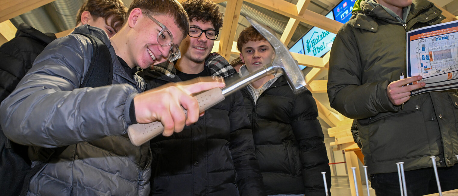Ein Schüler schlägt einen Nagel mit dem Hammer in einen Holzbalken.