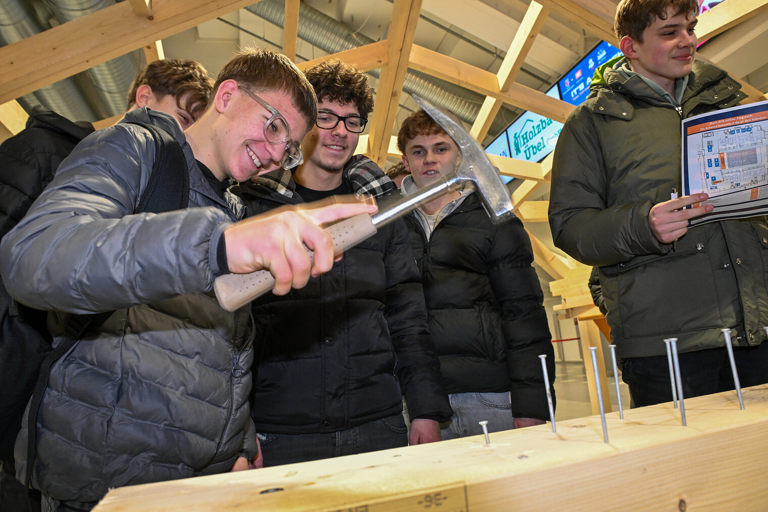 Ein Schüler schlägt einen Nagel mit dem Hammer in einen Holzbalken.