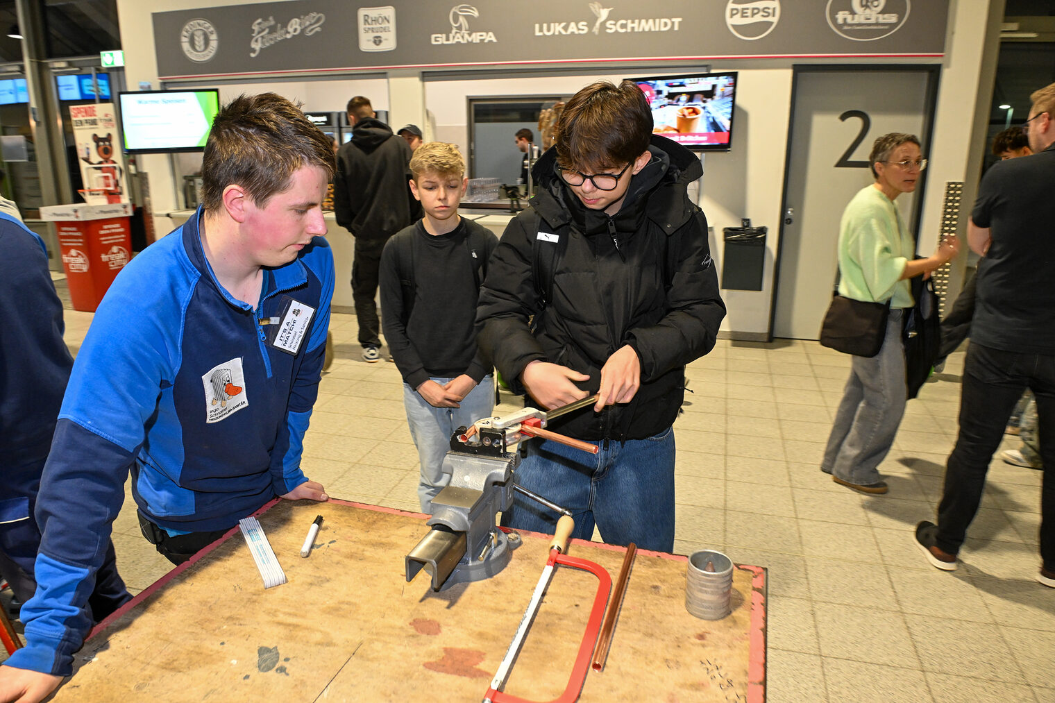 Ein Schüler biegt unter Anleitung ein Metallrohr im Schraubstock zurecht.