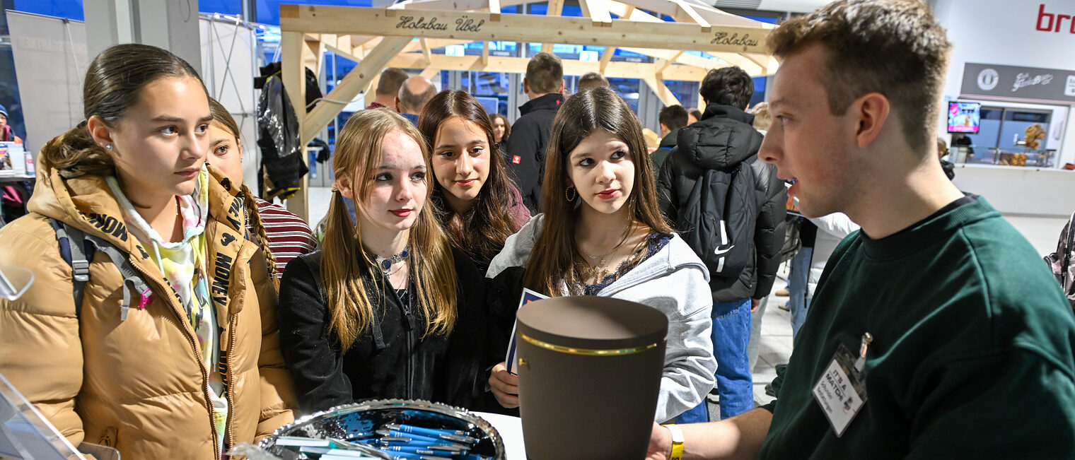 Ein Vertreter von Schunder Bestattungen zeigt Schülerinnen eine Urne.