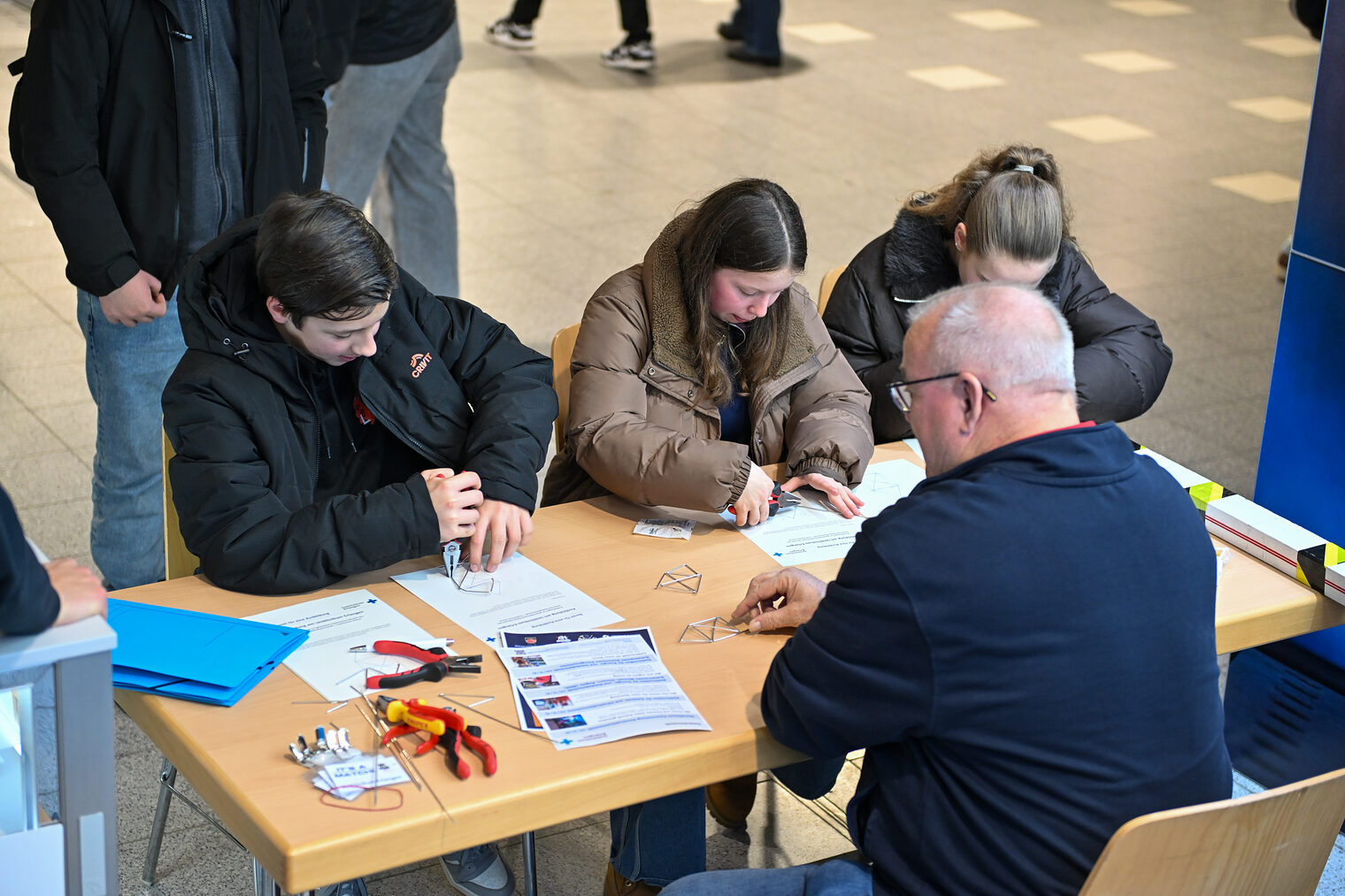 Schülerinnen und Schüler biegen Metalldrähte am Stand des Unicversitätsklinikums Erlangen zurecht.