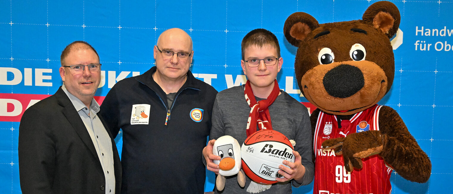 HWK-Vorstandsmitglied Jens Beland, Ingo Schnabel, ein Schüler mit dem Gewinnerball und Maskottchen Freaky