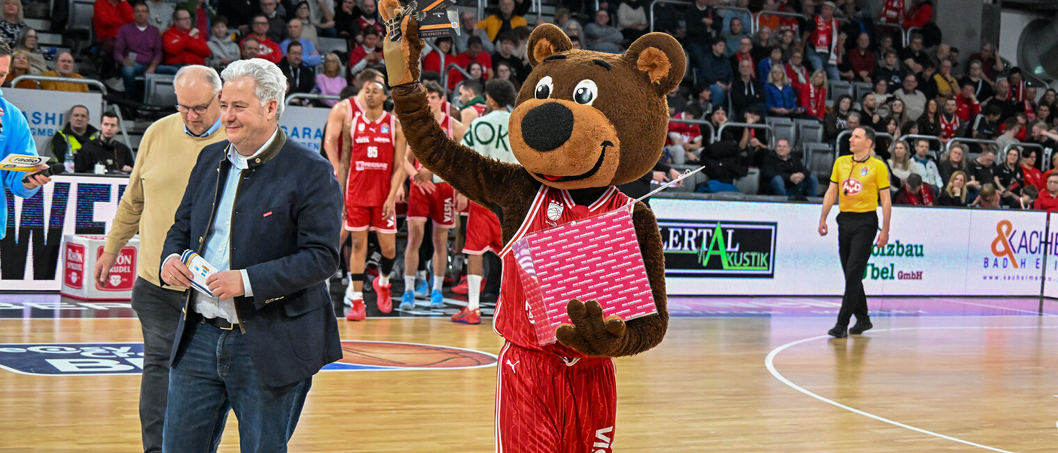 Reinhard Bauer, Matthias Graßmann und Maskottchen Freaky laufen über das Spielfeld.