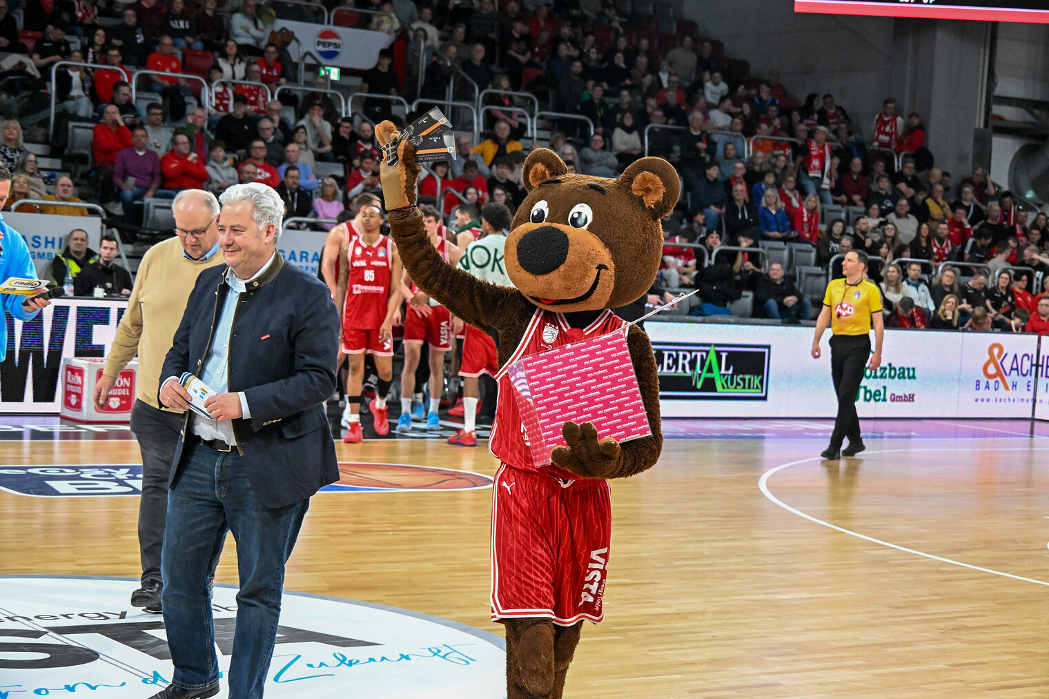 Reinhard Bauer, Matthias Graßmann und Maskottchen Freaky laufen über das Spielfeld.