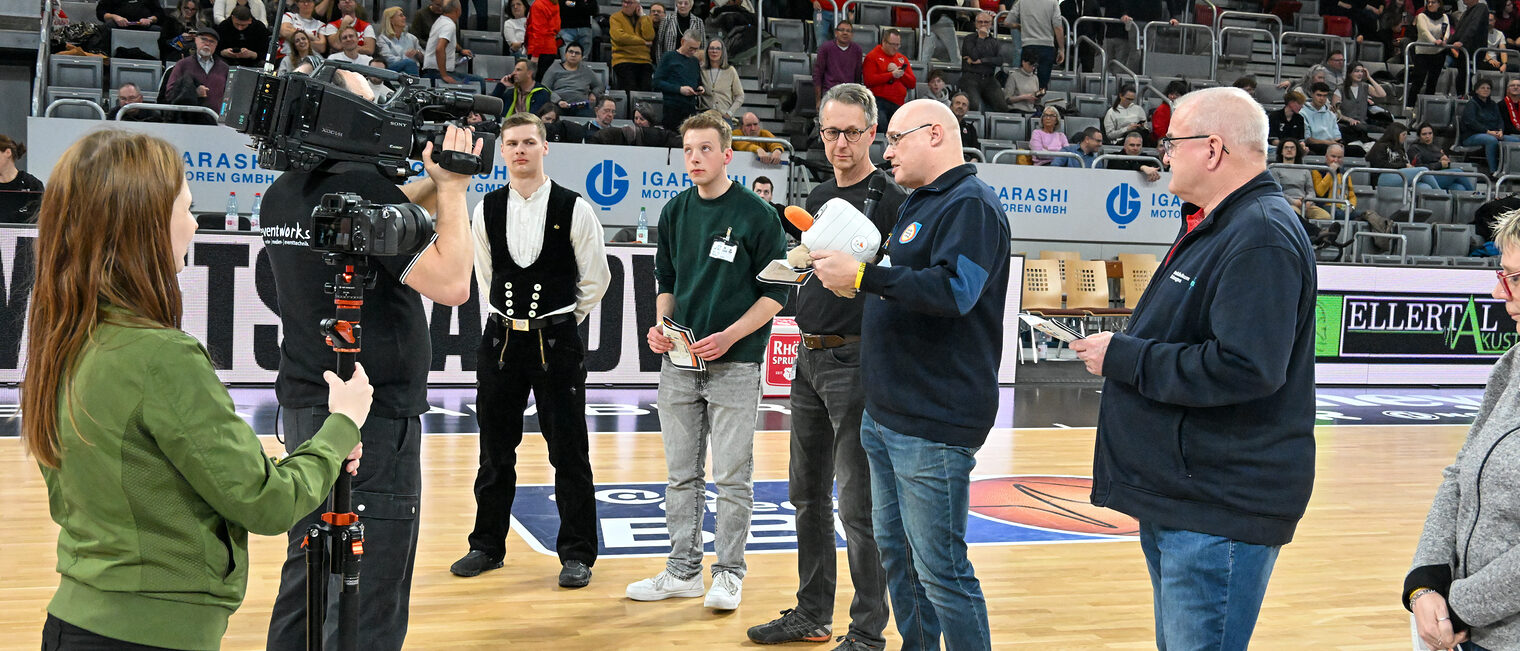 Die Vertreter der Betriebe stehen gemeinsam auf dem Spielfeld der Brose-Arena und stellen ihre Betriebe vor.
