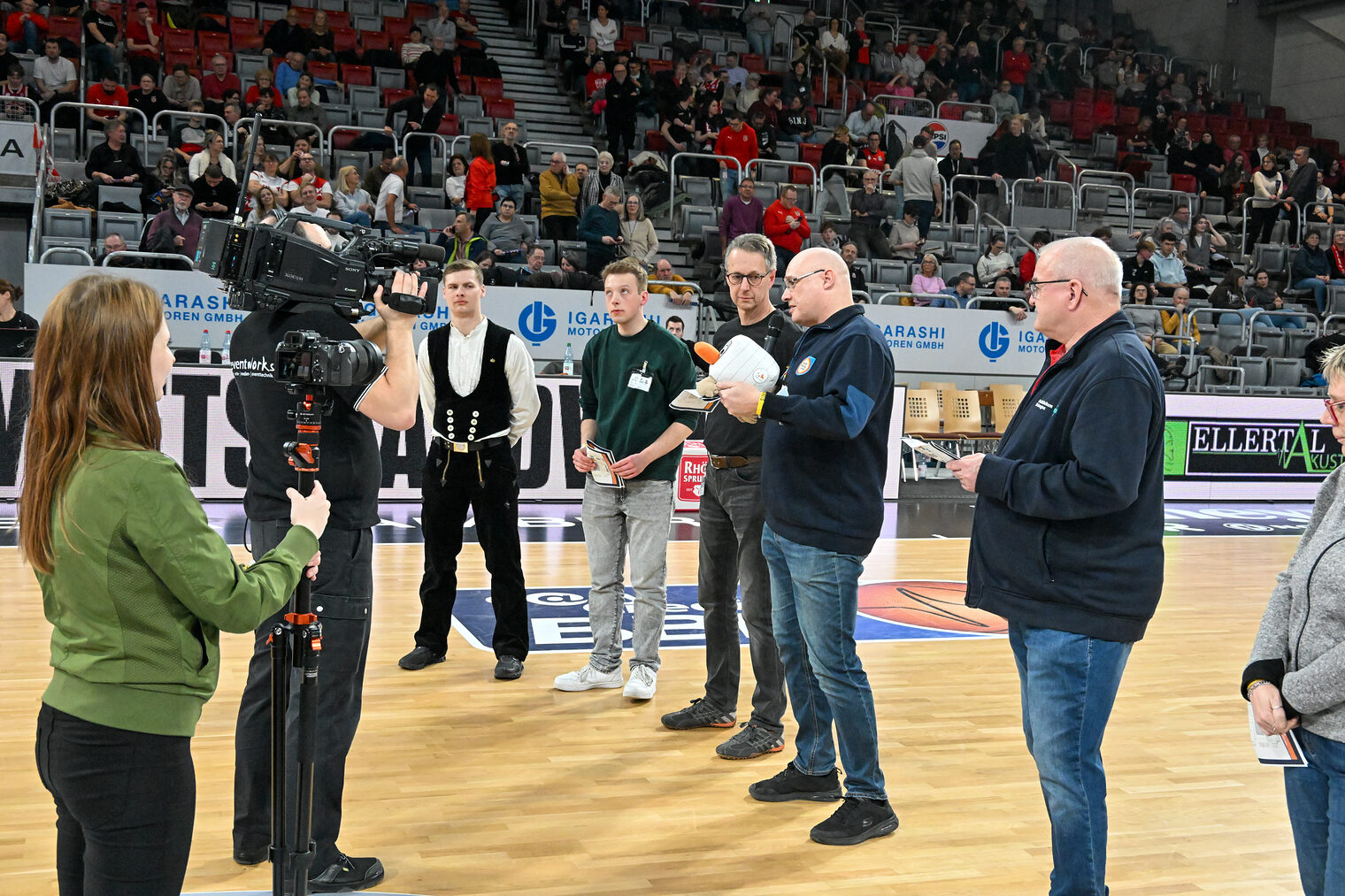 Die Vertreter der Betriebe stehen gemeinsam auf dem Spielfeld der Brose-Arena und stellen ihre Betriebe vor.