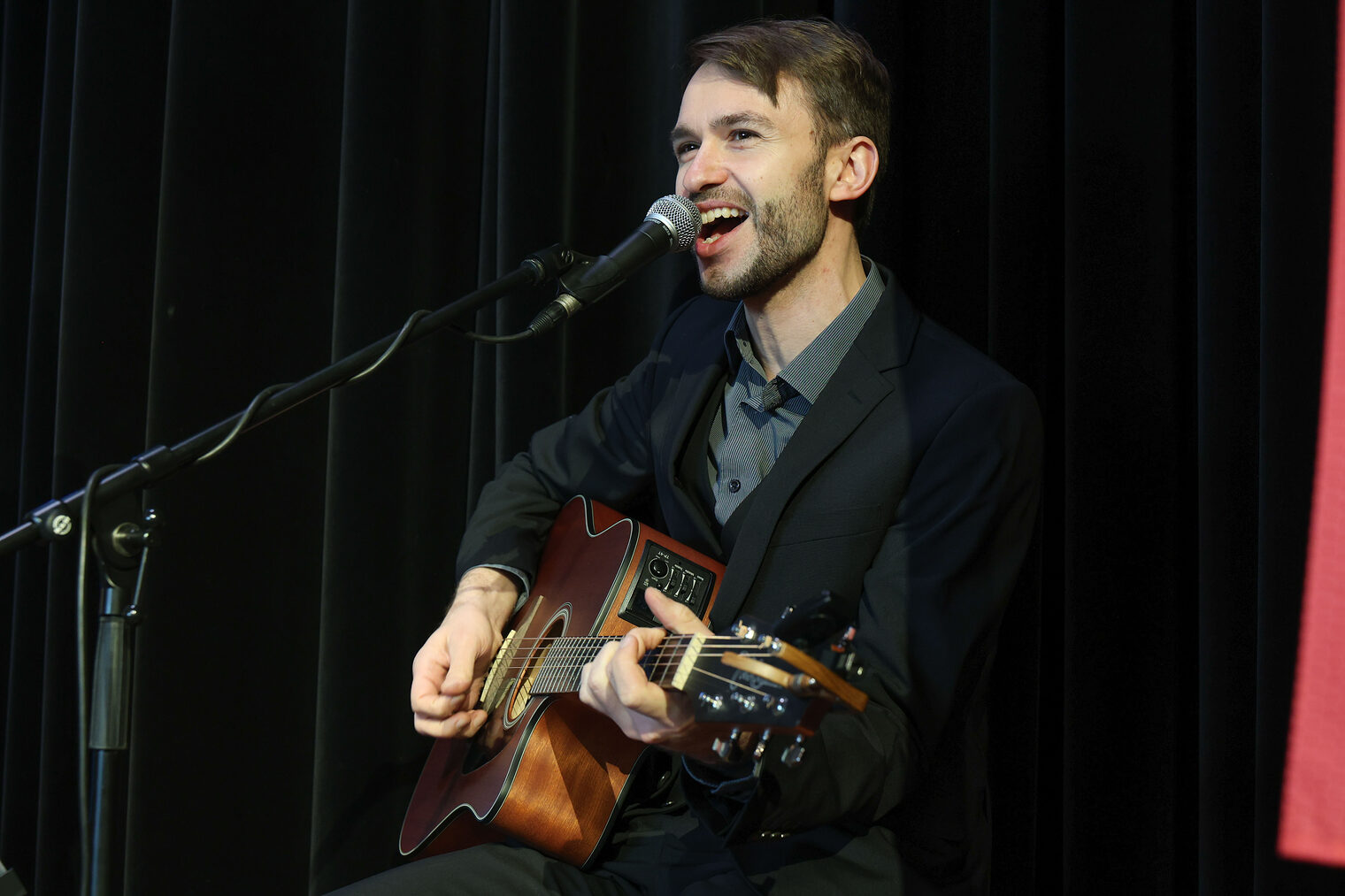 Ein Sänger von Liz Harmonics spielt Gitarre und singt ins Mikrofon.