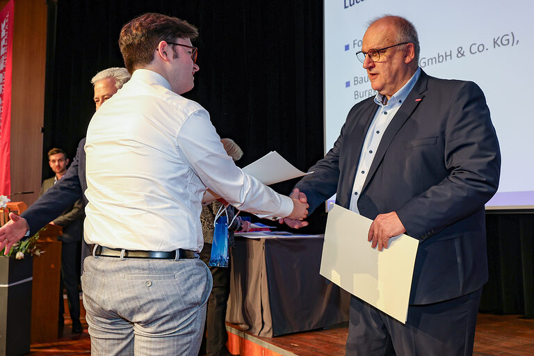 Kammersieger Luca Zwosta schütellt Hauptgeschäftsführer Reinhard Bauer die Hand.