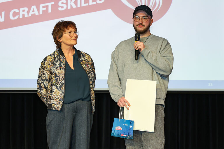 Max Sloot spricht auf der Bühne in ein Mikrofon.