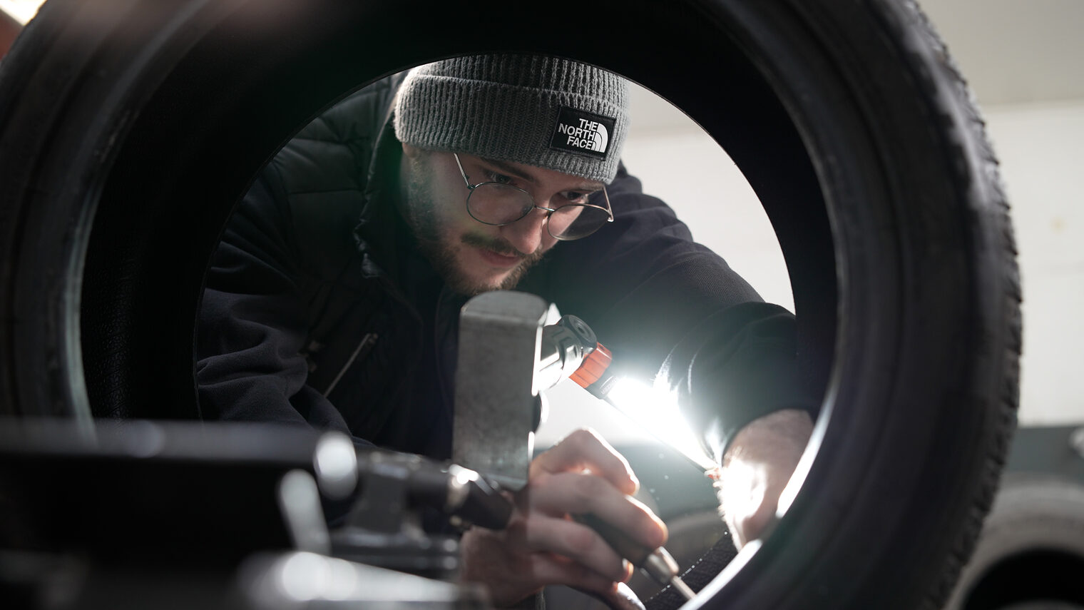 Max Sloot untersucht einen Reifen mit einer Lampe einen Reifen auf Schäden.