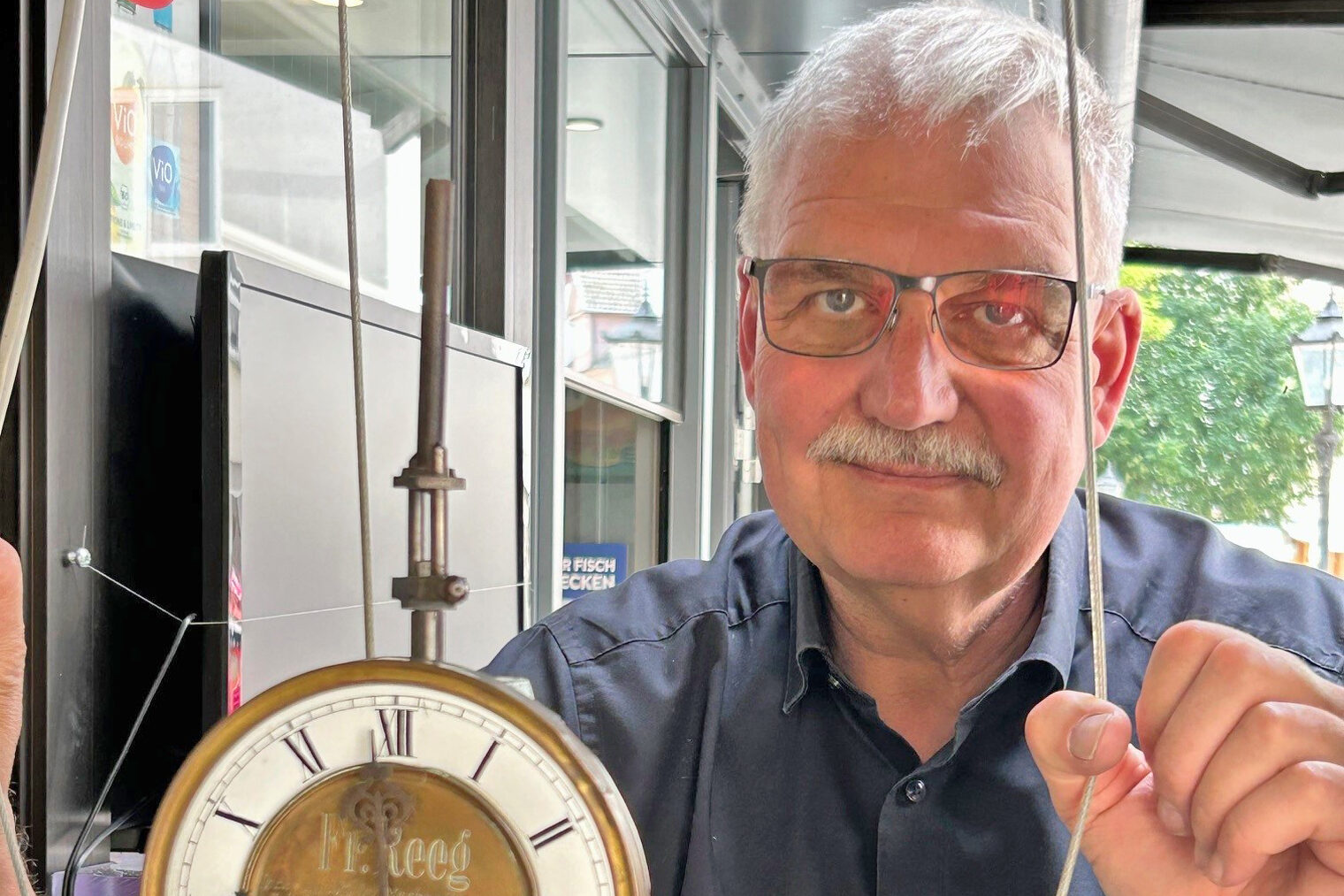 Stefan Stahl steht hinter dem Uhrwerk einer historischen Turmuhr aus dem Jahr 1902.