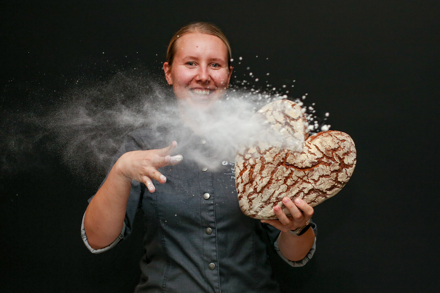 Eine Meisterschülerin hält ein Brot in Herzform in den Händen.