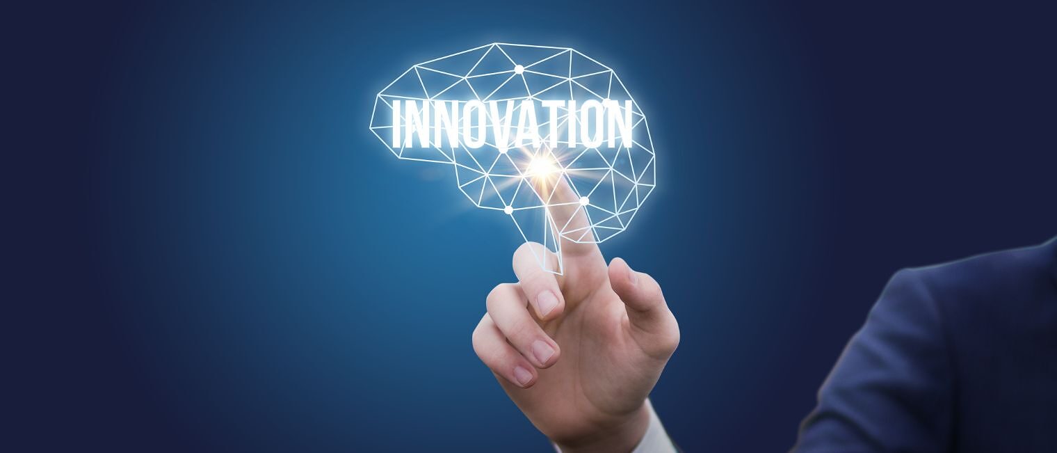 Eine Person zeigt auf ein Digitales Gehirn mit dem Wort Innovation.