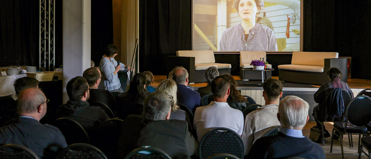 Die Zuschauer der Podiumsdiskussion sehen sich das Video von Bianca Krauss an.