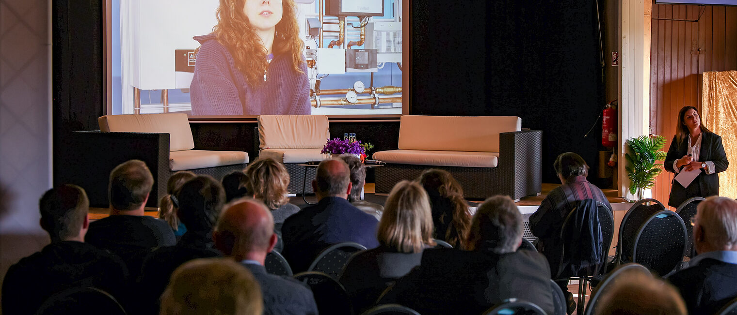 Die Zuschauer der Podiumsdiskussion sehen sich das Video von Kathrin Adam an.