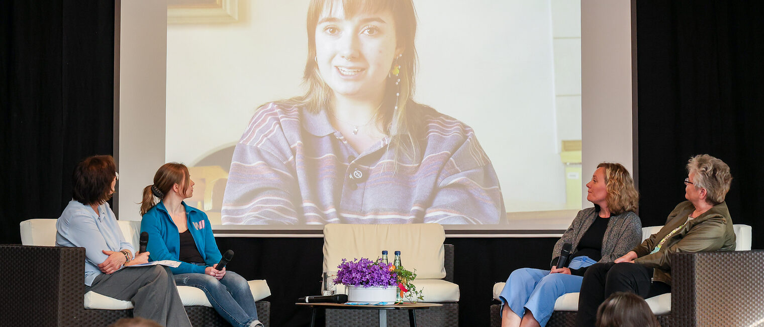 Die Podiumsteilnehmer und Gäste sehen sich das Video von Sarah Mergner an.