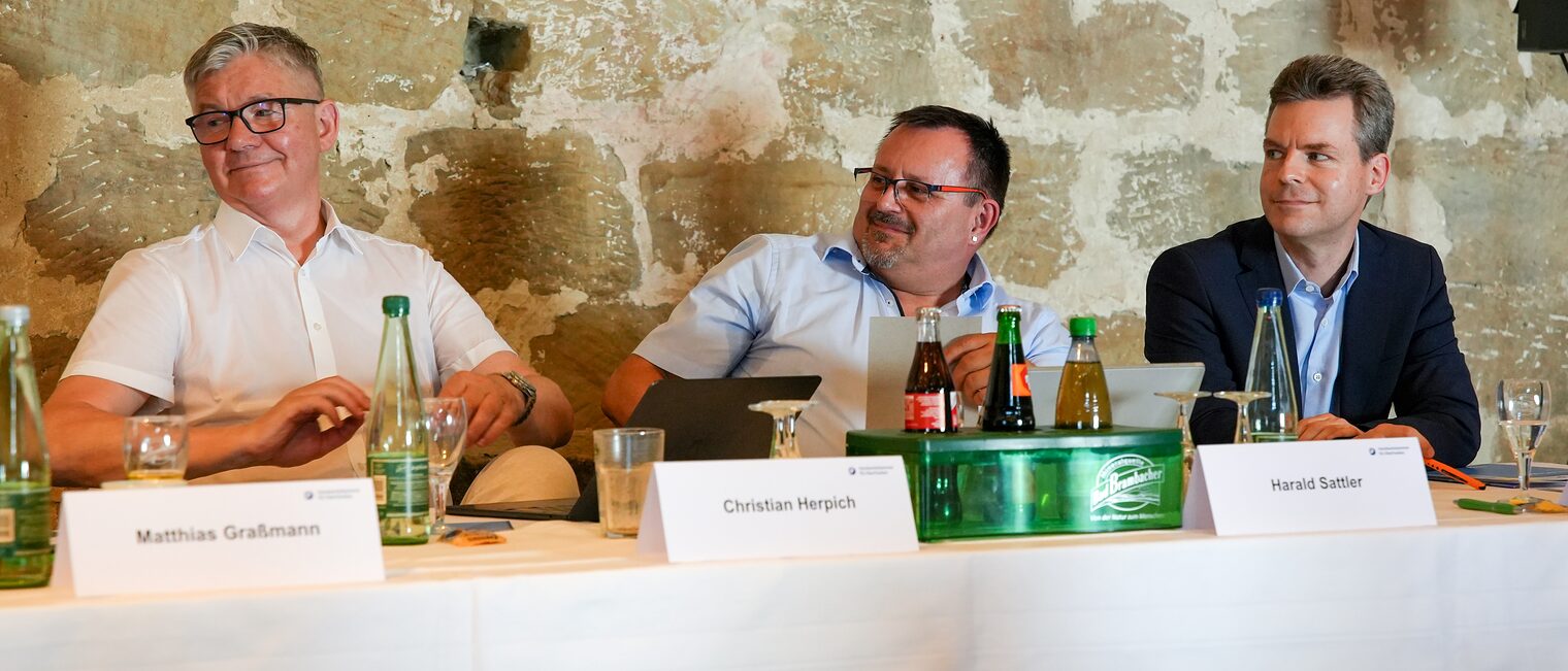 Christian Herpich, Harald Sattler und Sebastian Serfas sitzen an einem Tisch.
