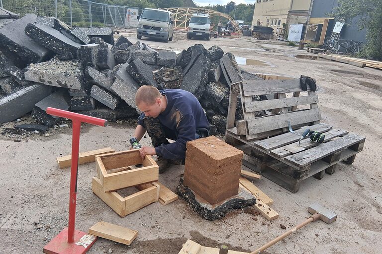 Ein junger Mann fertigt Rahmenhalterungen aus Holz für Lehmziegel.
