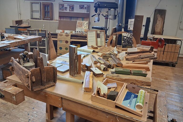 Ein Werktisch mit verschiedenen Werkzeugen und Teilen von Fensterrähmen. 