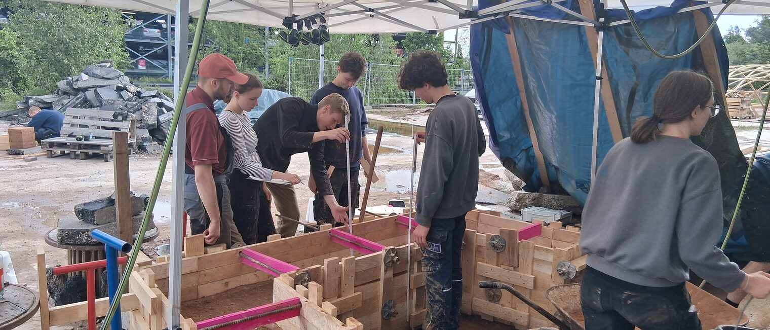 Mehrere Jugendliche bauen Mauern aus Lehm mit Stützkonstruktionen.