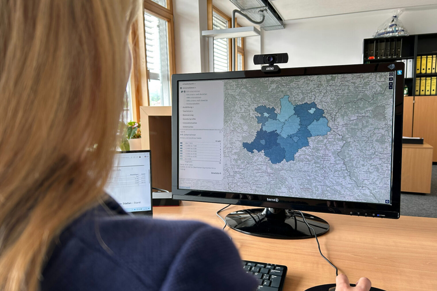 Eine Frau sieht sich den oberfränkischen Wirtschaftsatlas auf dem Computer an.