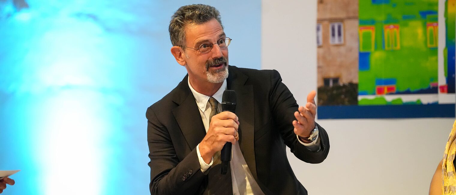 Professor Breitling hat ein Mikrofon in der Hand und erklärt etwas.