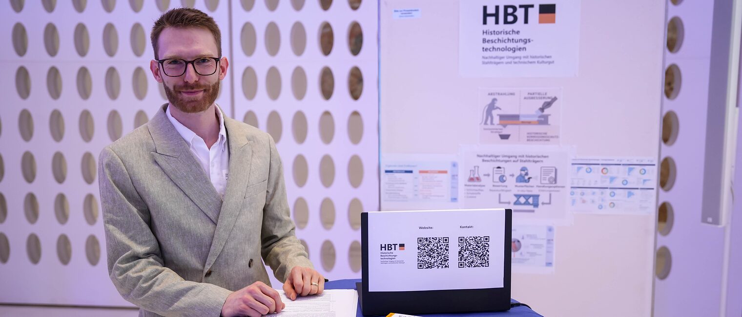 Ein Projektmitarbeiter steht an einem Stand von HBT Historische Beschichtungstechnologien.