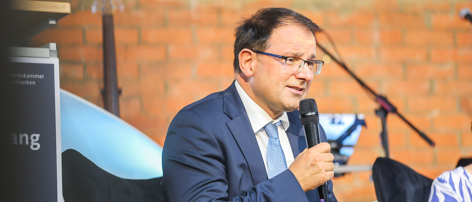 Martin Schöffel spricht auf dem Podium in ein Mikrofon.