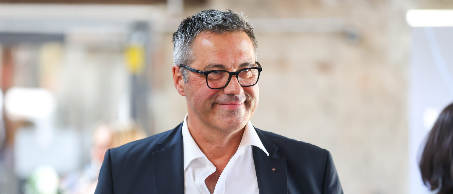 Ein Gast des Sommerempfangs lächelt in die Kamera.