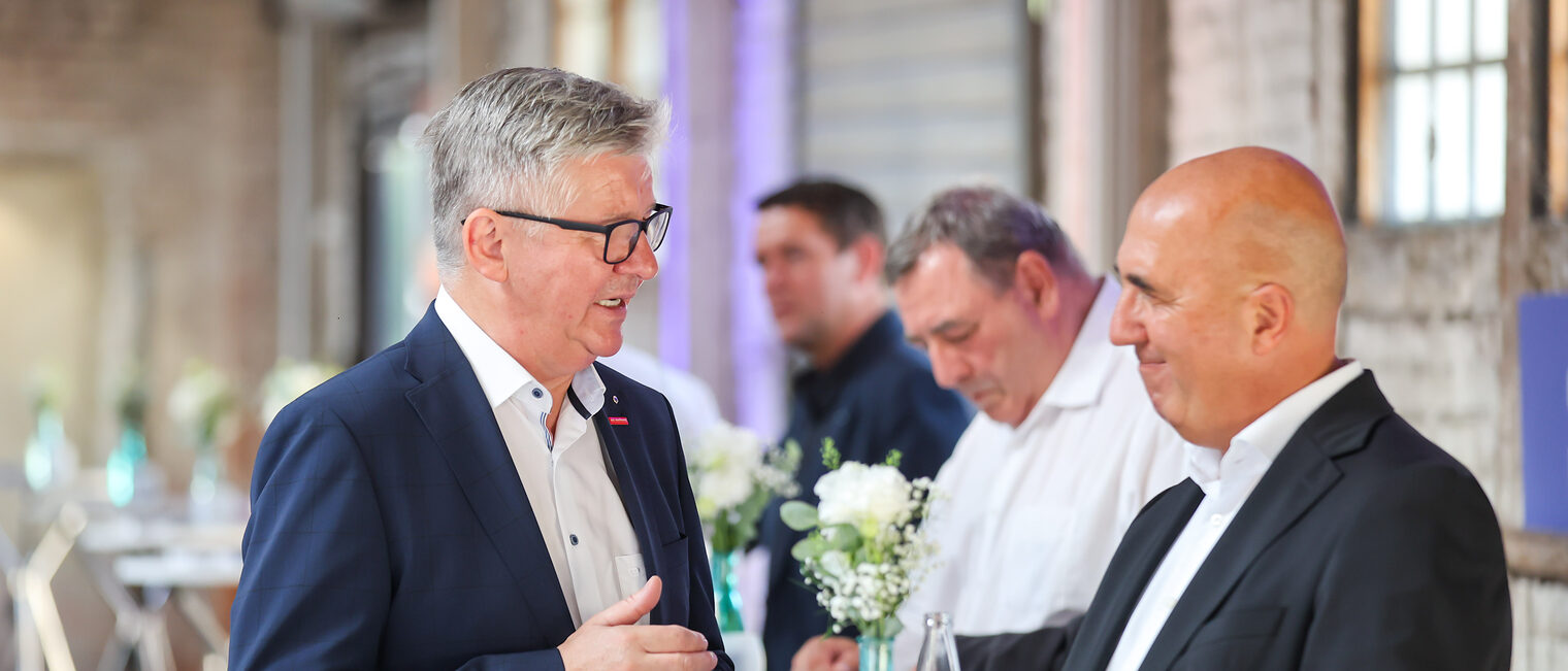 Christian Herpich und ein Gast des Sommerempfangs unterhalten sich.