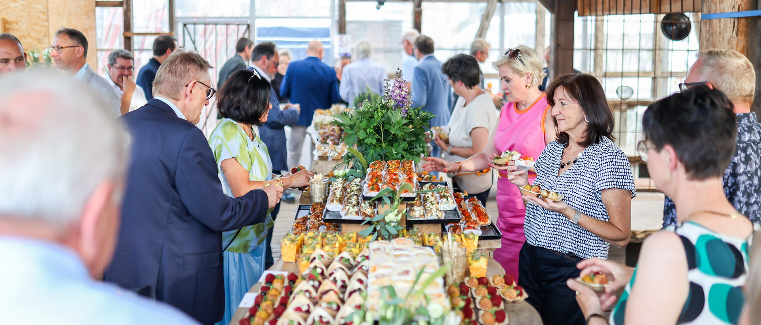Gäste des Sommerempfangs stehen am Buffet.