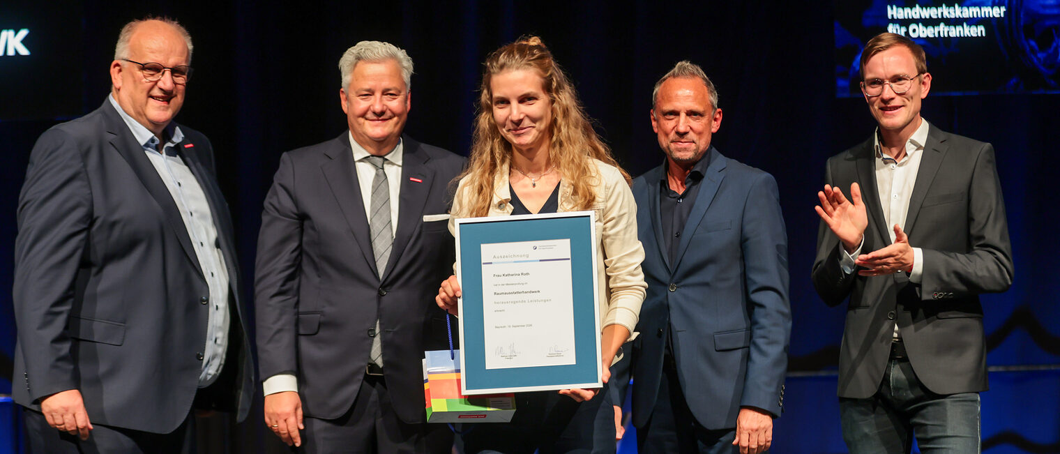 Jungmeisterin Katharina Roth präsentiert ihre Ehrenurkunde mit Gratulanten auf der Bühne.