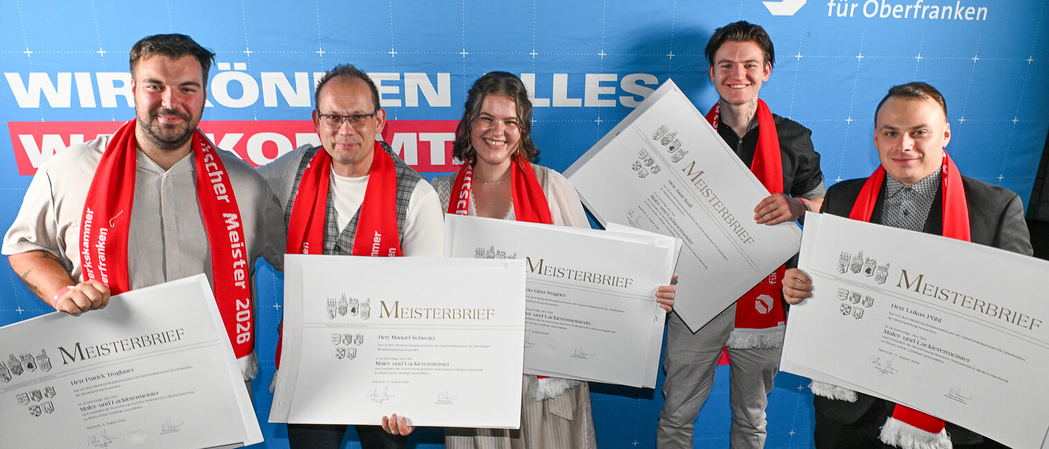 Die Jungmeisterinnen und Jungmeister im Maler- und Lackiererhandwerk posieren für ein Gruppenfoto vor einer Fotowand.