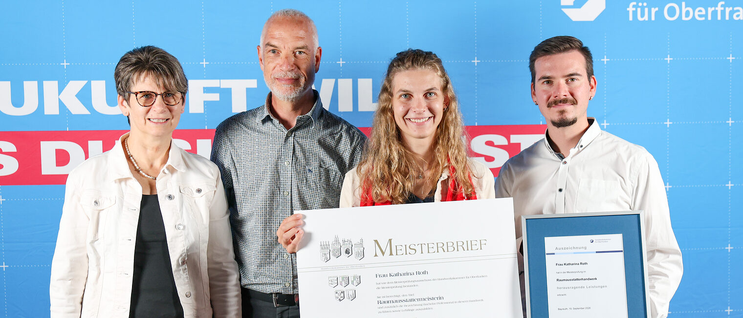 Jungmeisterin Katharina Roth posiert mit ihrer Familie vor einer Fotowand.